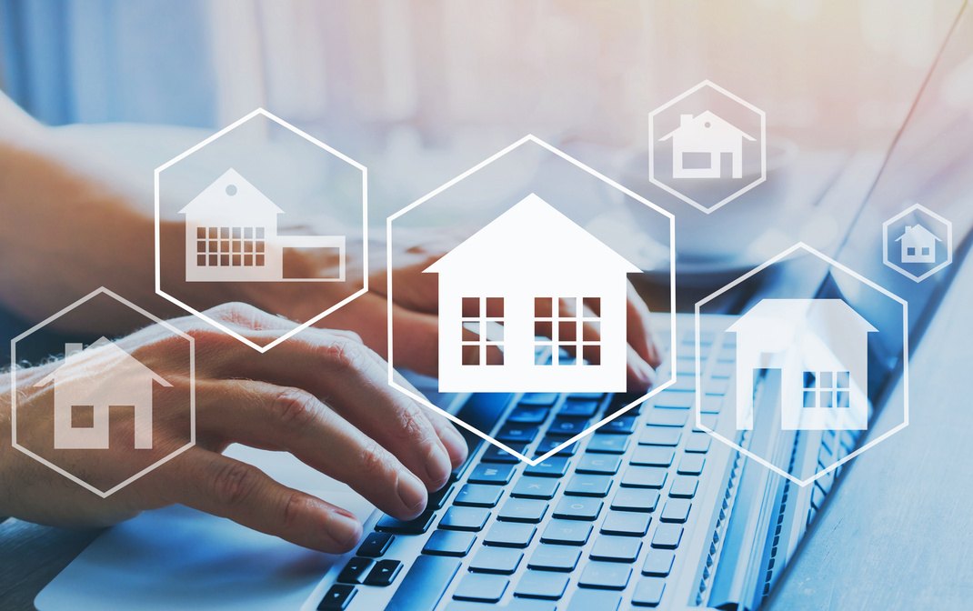 Hands typing on a laptop with digital house icons