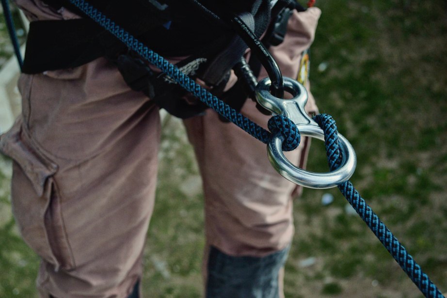 Blue climbing rope attached to a carabiner on a safety harness
