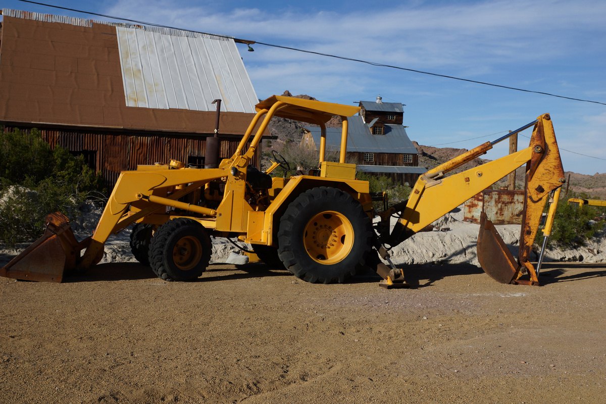 Yellow backhoe loader on a dirt lot
